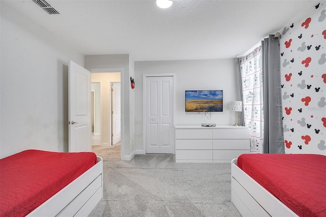 bedroom featuring light carpet, a closet, and a textured ceiling