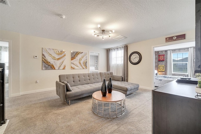 living room featuring light colored carpet, a textured ceiling, and a healthy amount of sunlight