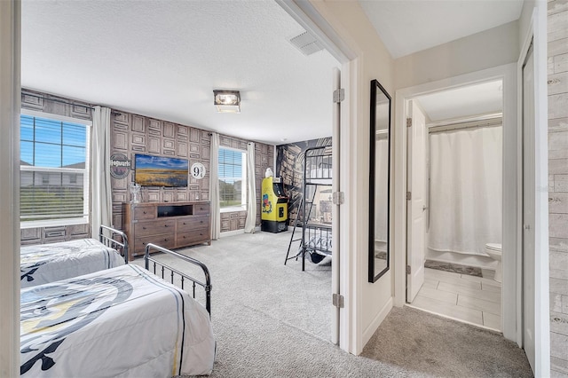 bedroom with light carpet, a textured ceiling, and multiple windows