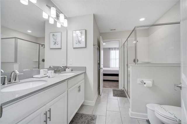 bathroom featuring vanity, toilet, a shower with door, and tile patterned floors