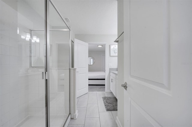 bathroom featuring tile patterned floors, vanity, a shower with shower door, and a textured ceiling