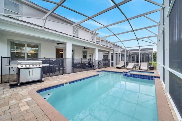 view of swimming pool with ceiling fan, a patio, an in ground hot tub, grilling area, and glass enclosure