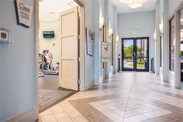 hallway with light wood-type flooring, high vaulted ceiling, and french doors