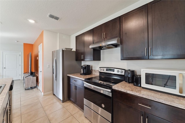 kitchen with a textured ceiling, dark brown cabinetry, light tile patterned floors, and stainless steel appliances