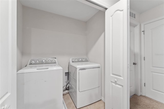 clothes washing area featuring light colored carpet and washing machine and clothes dryer