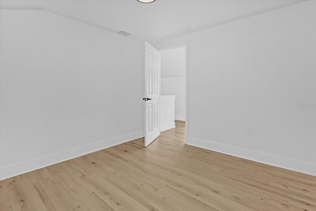 empty room featuring vaulted ceiling and light hardwood / wood-style floors