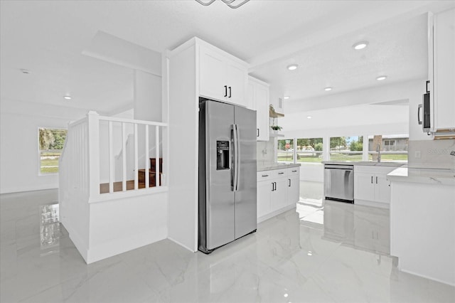 kitchen with light stone counters, stainless steel appliances, and white cabinets