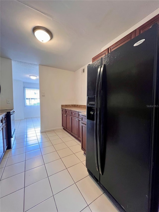 kitchen featuring black refrigerator with ice dispenser, light tile patterned flooring, and stainless steel electric range