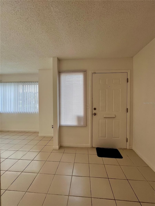 foyer entrance with a textured ceiling and light tile patterned floors