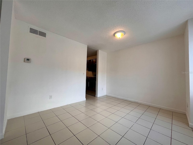 empty room featuring a textured ceiling and light tile patterned flooring