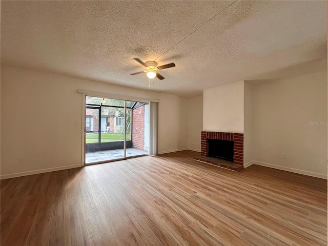 unfurnished living room featuring light wood-type flooring, ceiling fan, a fireplace, and a textured ceiling