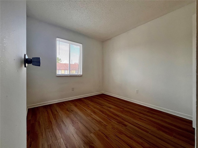 spare room with a textured ceiling, baseboards, and dark wood finished floors