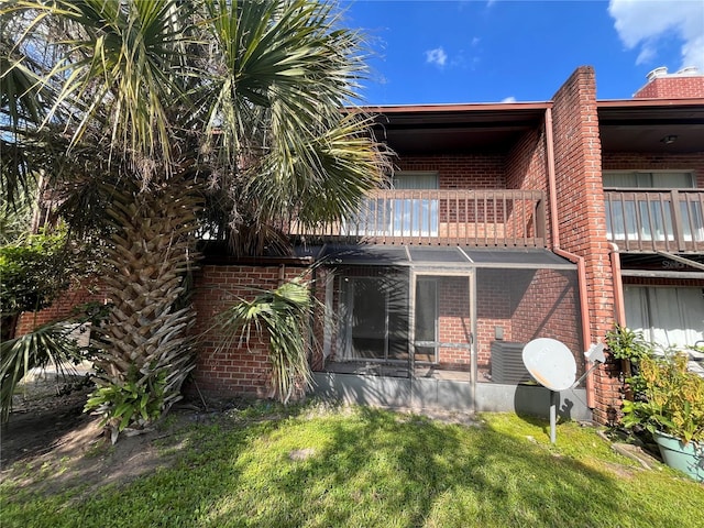 rear view of property featuring a balcony and a yard