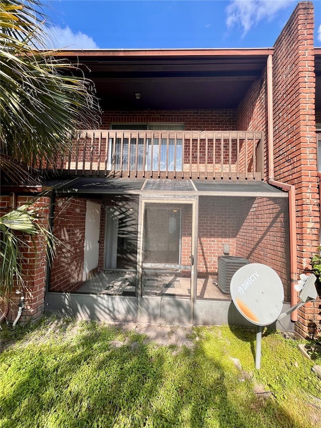 rear view of house featuring brick siding, central AC unit, a patio, and a balcony