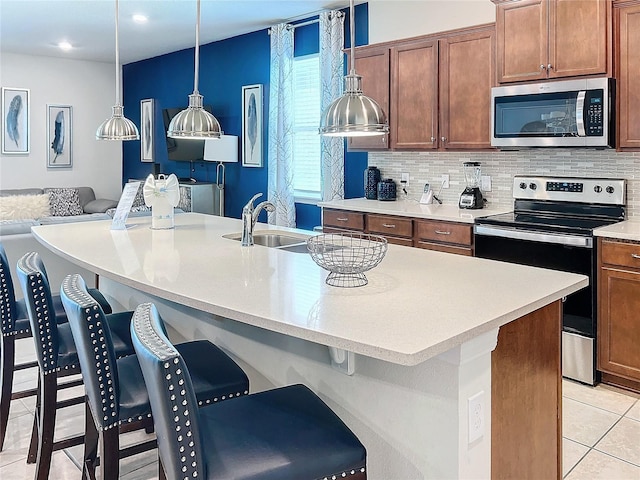 kitchen featuring appliances with stainless steel finishes, light tile patterned flooring, sink, a kitchen breakfast bar, and pendant lighting