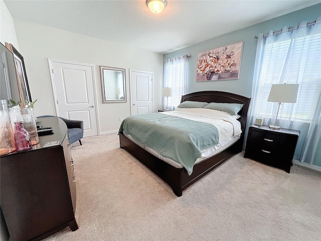 bedroom featuring multiple windows, a closet, and light colored carpet