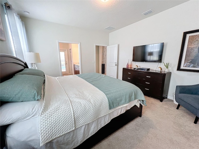 bedroom featuring light carpet, a textured ceiling, and ensuite bath