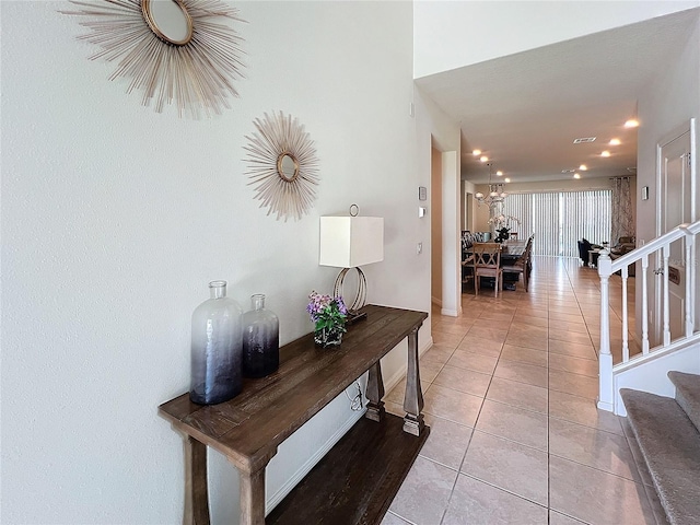 hallway with an inviting chandelier and light tile patterned flooring