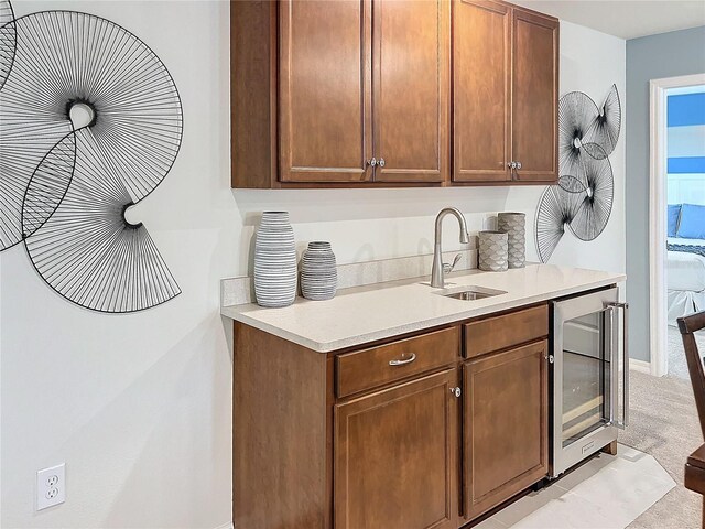 kitchen with sink, light colored carpet, and beverage cooler