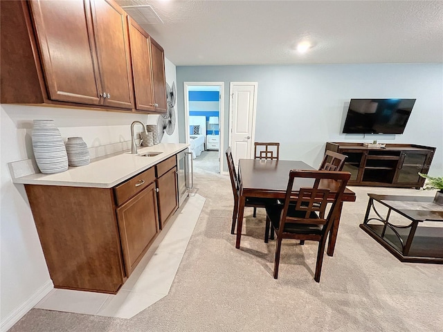 kitchen featuring sink, light colored carpet, and a textured ceiling