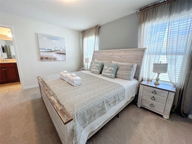 bedroom featuring ensuite bathroom and light carpet