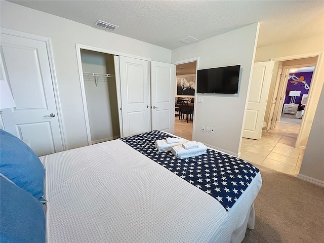 bedroom with a closet, a textured ceiling, and light colored carpet