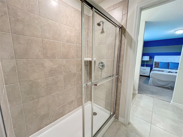 bathroom featuring tile patterned floors, a shower with shower door, and a textured ceiling