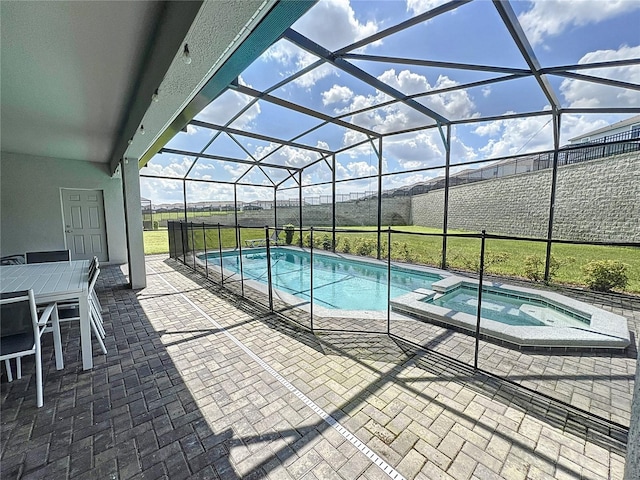 view of pool with an in ground hot tub, a patio area, and glass enclosure