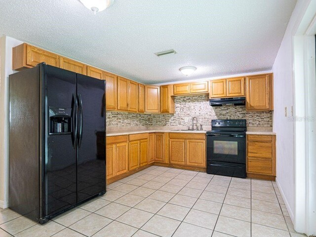 kitchen with light tile patterned flooring, backsplash, a textured ceiling, black appliances, and sink