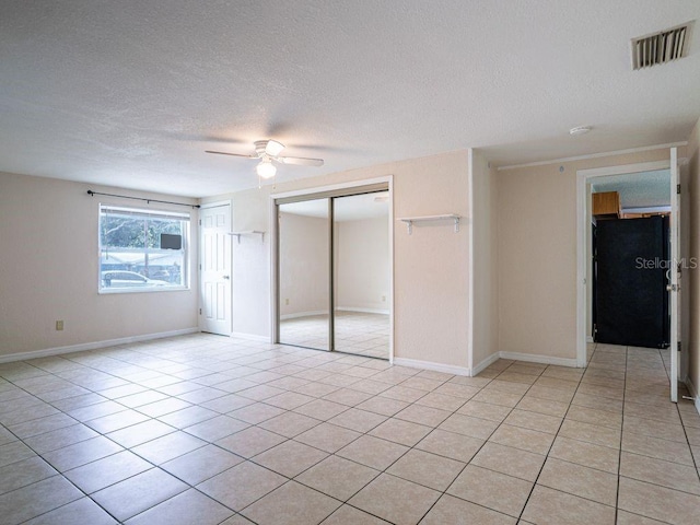 unfurnished room with ceiling fan, a textured ceiling, and light tile patterned floors