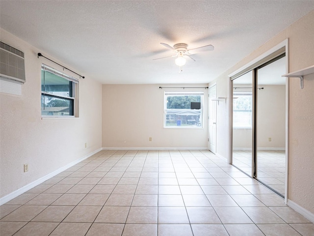 unfurnished bedroom with ceiling fan, a textured ceiling, multiple windows, and light tile patterned flooring