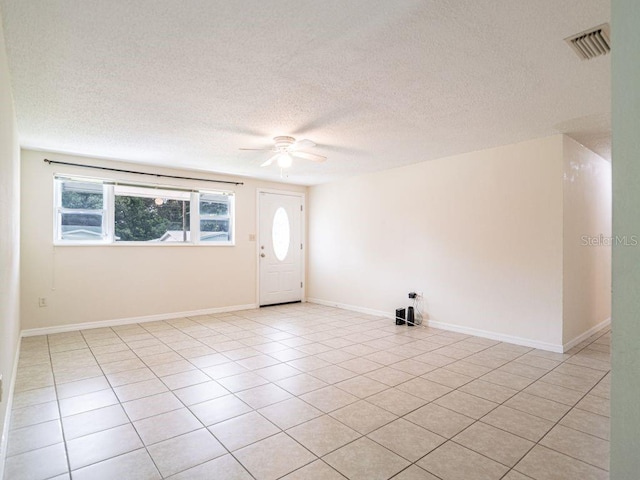 empty room with ceiling fan, a textured ceiling, and light tile patterned flooring