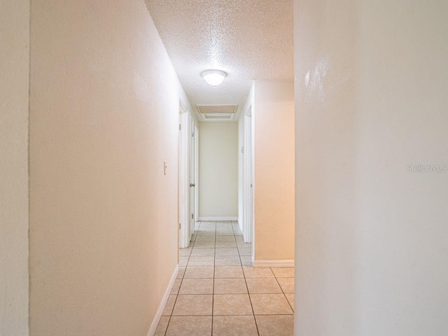 hall featuring a textured ceiling and light tile patterned floors