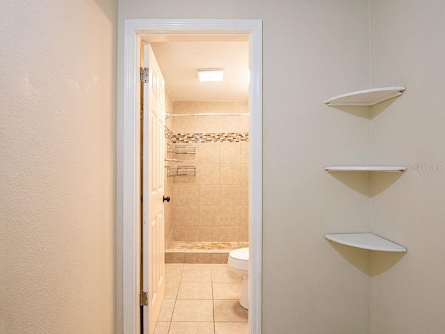 bathroom with a tile shower, tile patterned floors, and toilet