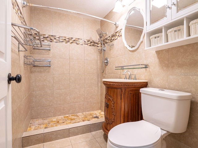 bathroom with tile walls, tile patterned floors, tiled shower, vanity, and toilet