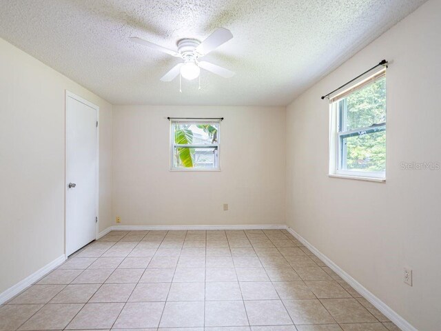 tiled empty room featuring ceiling fan and a textured ceiling