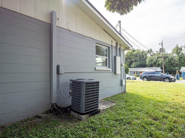 view of property exterior with a lawn and central AC