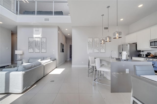 interior space with light tile patterned flooring, sink, white cabinets, hanging light fixtures, and stainless steel appliances