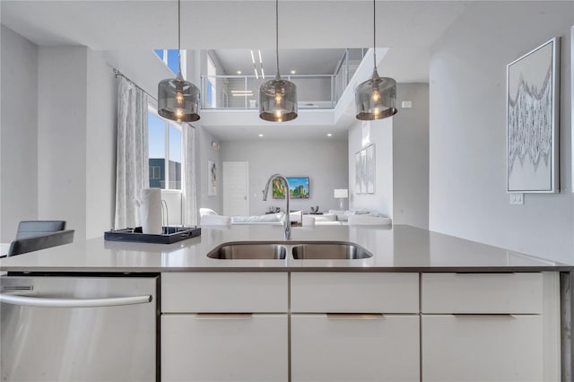 kitchen featuring sink, hanging light fixtures, white cabinetry, and stainless steel dishwasher