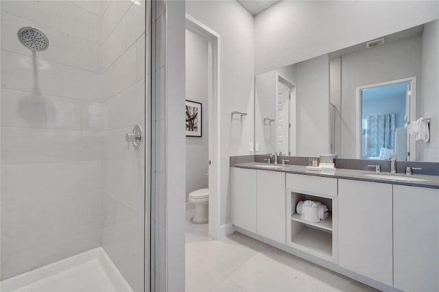 bathroom with tiled shower, vanity, toilet, and tile patterned floors