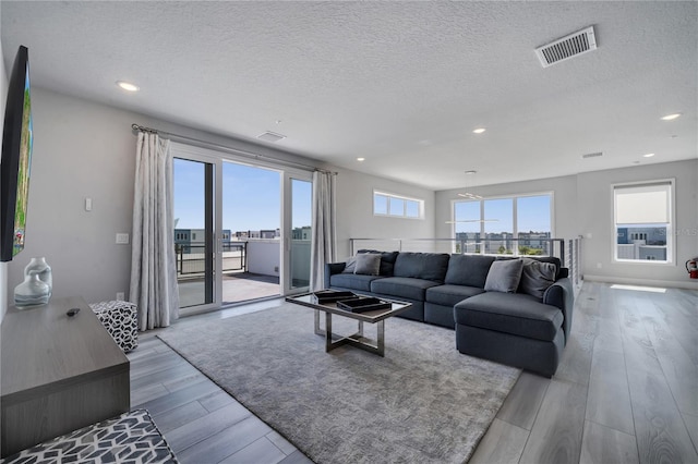 living room featuring light wood-type flooring and a textured ceiling