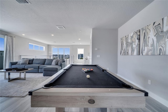 game room with a textured ceiling, light wood-type flooring, and pool table