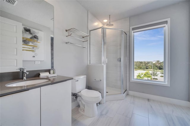 bathroom featuring a healthy amount of sunlight, vanity, toilet, and a shower with door