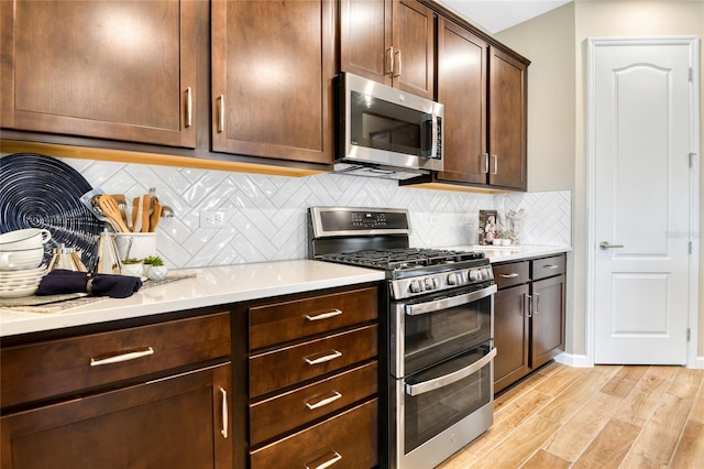 kitchen featuring appliances with stainless steel finishes, backsplash, light hardwood / wood-style floors, and dark brown cabinetry