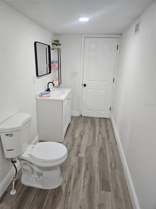 bathroom with wood-type flooring, vanity, and toilet