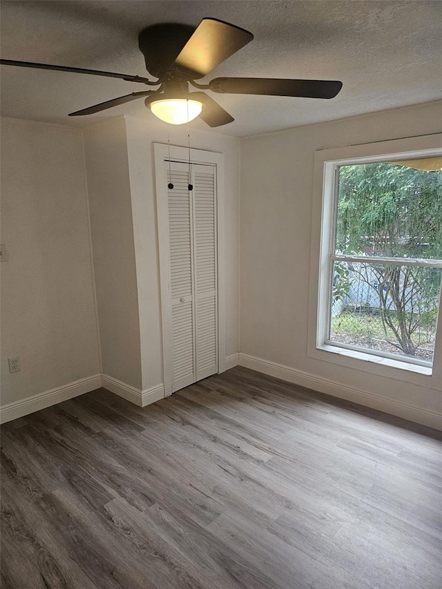 unfurnished bedroom with ceiling fan, a closet, and wood-type flooring