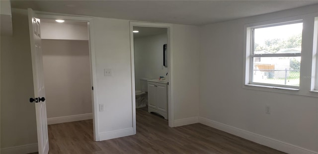 unfurnished bedroom featuring connected bathroom, a spacious closet, and dark hardwood / wood-style flooring