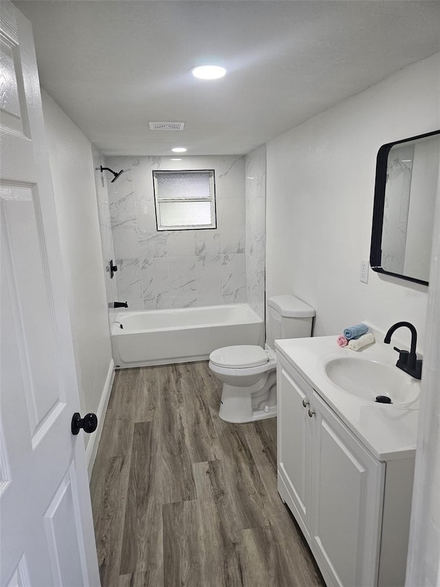 full bathroom with wood-type flooring, vanity, toilet, and tiled shower / bath combo