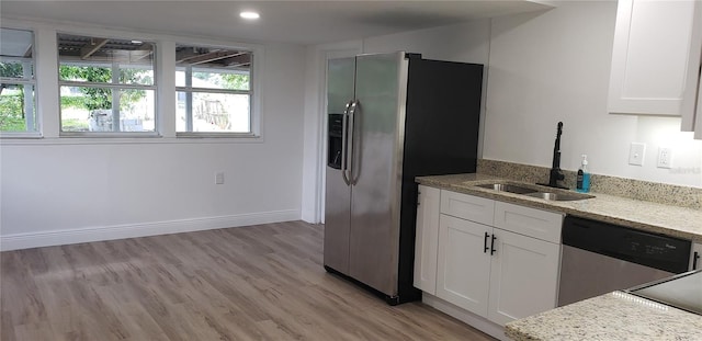 kitchen featuring sink, white cabinetry, light hardwood / wood-style flooring, appliances with stainless steel finishes, and light stone countertops