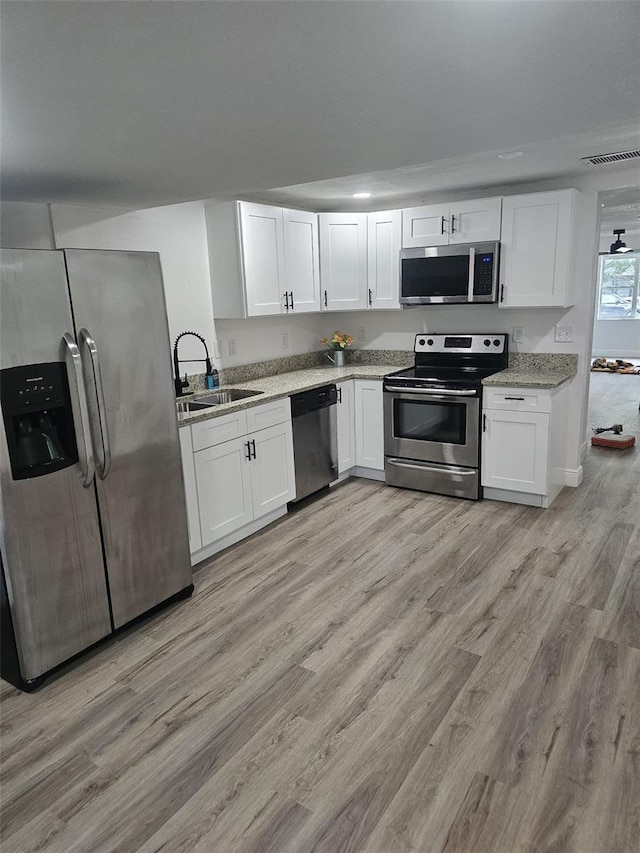 kitchen featuring light wood-type flooring, sink, stainless steel appliances, and white cabinets